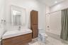 Floating vanity with wood-finish cabinetry, rectangular integrated sink, tall linen storage cabinet, and patterned tile flooring