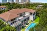 Two-story exterior featuring a tile roof, dual-level balconies with decorative metal railings, ground-level covered patio, and rectangular swimming po