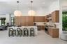 Kitchen featuring wood-finish cabinetry, a waterfall-edge island with a metallic faucet, stone-patterned backsplash, stainless steel professional-styl