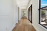 Hallway featuring wood-finish flooring, recessed lighting, and expansive floor-to-ceiling black-framed glass doors