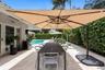 Covered stone patio featuring a swimming pool, integrated landscaping, and French doors