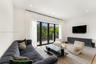 Living area featuring recessed lighting and black-framed glass double doors opening to a balcony with decorative metal railings