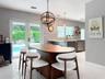 Orbital metal chandelier, solid-surface breakfast bar, stainless steel dishwasher, glass French doors, and porcelain tile flooring