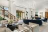 High-ceilinged room featuring a double-height staircase with wood-finish railings, recessed lighting, expansive glass-paned entrance doors, and a cust
