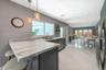 Kitchen featuring stone-finish countertops with an integrated breakfast bar, dark-tone cabinetry, stainless steel dishwasher, dual pendant lighting, a