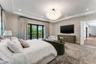 Tray ceiling with recessed lighting, custom multi-globe chandelier, patterned wall treatment, and floor-to-ceiling glass panel doors opening to a balc