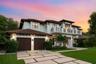Two-story exterior featuring a tile roof, stucco finish, expansive second-story balcony with metal railings, and a multi-car garage with wood-finish d