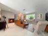 Living space featuring large-format tile flooring, a recessed fireplace with brick surround, and a bay window with a built-in bench