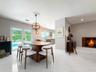 Large-format tile flooring, brick-surround masonry fireplace, spherical metal chandelier, and double-glass doors opening to exterior pool area