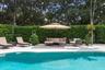 Swimming pool with stone paver decking and high hedge perimeter fencing