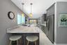 Kitchen featuring charcoal-toned cabinetry, light-toned stone-finish countertops, stainless steel appliances, polished tile flooring, and dual glass p