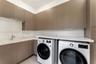 L-shaped workspace featuring extensive textured cabinetry, white stone-surface countertops, an undermount utility sink, and dedicated laundry applianc
