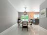 Large-format porcelain tile flooring, spherical metal-frame pendant lighting, glass-paned double doors, and a stone-topped kitchen peninsula with inte