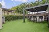 Outdoor area featuring an artificial turf lawn, a metal pergola, a built-in kitchen island, and privacy wood fencing