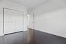 Interior space featuring dark wood-finish flooring, white walls, and a white six-panel bifold closet door