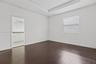 Room featuring tray ceilings, wood-finish flooring, and horizontal banded window shades