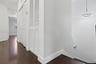 Interior hall featuring wood-finish flooring, white louvered-door closets, and a circular LED pendant light fixture