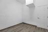 Interior space featuring textured walls, wood-finish flooring, and a six-panel door with brushed metal hardware