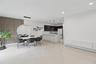 Open-concept area featuring oversized neutral floor tiling, a vertical wood-slat accent wall, recessed lighting, and a kitchen equipped with dark cabi