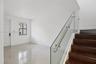 Staircase featuring dark wood-finish treads and a frameless glass railing with a metallic handrail, complemented by large-format tile flooring