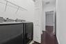 Dedicated laundry area featuring dark-toned washer and dryer, white bi-fold closet doors, wire shelving, and wood-finish flooring