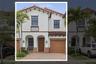 Stucco exterior featuring arched entryway detailing, red-tiled roof, paver driveway, and a single-car garage