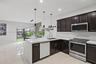 Kitchen featuring dark-finish cabinetry, white solid-surface countertops, stainless steel appliances, recessed ceiling lighting, and large-format tile