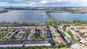 Aerial perspective of multi-family residences featuring tile roofing, paved streets, manicured green space, and proximity to large bodies of water
