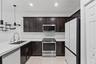 Kitchen featuring dark-finish cabinetry, stone-style countertops, stainless steel appliances, a recessed sink with a high-arch pull-down faucet, and i