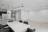 Modern open-concept area featuring large-format tile flooring, a kitchen peninsula with a stone-surfaced waterfall edge, custom pendant lighting, and 