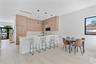 Modern kitchen featuring wood-finish cabinetry, a white countertop island, integrated lighting pendants, and light-toned tile flooring