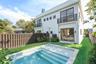 Modern two-story exterior featuring a private swimming pool with built-in steps, second-floor balconies with horizontal railings, sliding glass doors,