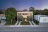Two-story modern architectural exterior featuring a smooth stucco facade, black metal privacy screening, sliding glass balcony doors, and dual concret