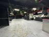 Open-concept interior featuring exposed ceiling rafters, diamond-plate metal bar detailing, and geometric wall paneling
