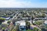 Aerial perspective of a multi-story residence featuring a flat roofline, two levels of balcony structures, a ground-level rectangular swimming pool, a