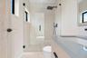 Bathroom featuring a wood-finish vanity with a stone countertop, a glass-enclosed walk-in shower with matte black rainfall showerhead, and high-contra