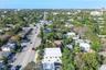 Aerial perspective of a multi-story structure featuring a flat roof and concrete-finish exterior, situated on a lot with established canopy trees and 