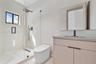 Modern bathroom featuring a wood-finish vanity, solid-surface countertop, frameless glass-enclosed shower, wall-mounted matte black fixtures, and a sl