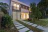 Contemporary two-story exterior featuring a smooth stucco finish, horizontal metal louvered privacy screening, glass sliding doors, and a linear paver