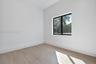 Interior space featuring neutral wall tones, wood-finish flooring, and a black-framed window