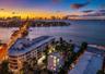 Aerial perspective of waterfront multi-story building featuring wrap-around balconies and structural skyline backdrop