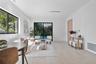 Open-concept interior featuring light wood-finish flooring, recessed lighting, expansive black-framed windows, and sliding glass doors with exterior p