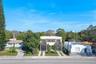 Modern two-story structure featuring a stucco exterior, integrated balconies, large-format glass doors, and a paved dual-track driveway