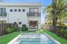 Contemporary two-story exterior featuring smooth stucco finish, black horizontal balcony railings, sliding glass doors, a rectangular swimming pool, a