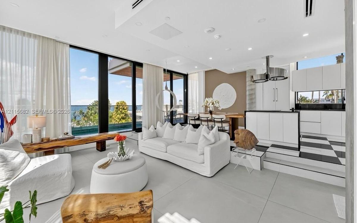 Open-concept living area featuring floor-to-ceiling windows, high-gloss white cabinetry, a tiered kitchen platform, checkered tile flooring, and reces