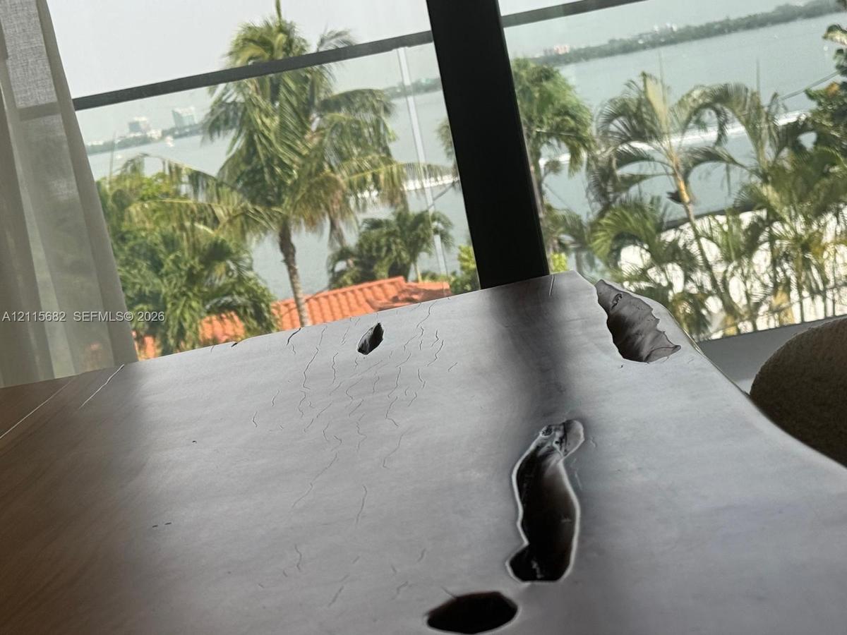 Floor-to-ceiling windows with expansive water scenery and palm tree backdrop