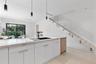 Modern kitchen island featuring a quartz countertop, black undermount sink, and matte black faucet, complemented by white cabinetry, wood-finish floor
