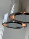 Polished chrome tiered pendant lighting fixture featuring circular metallic bands and integrated illumination