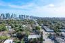 Aerial perspective featuring an urban skyline backdrop and mature landscape canopy