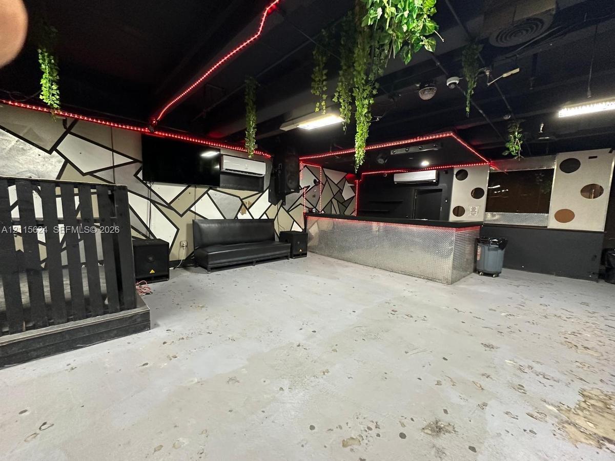 Built-in bar with metallic frontage, geometric patterned wall accents, exposed ceiling design, and wall-mounted climate control units